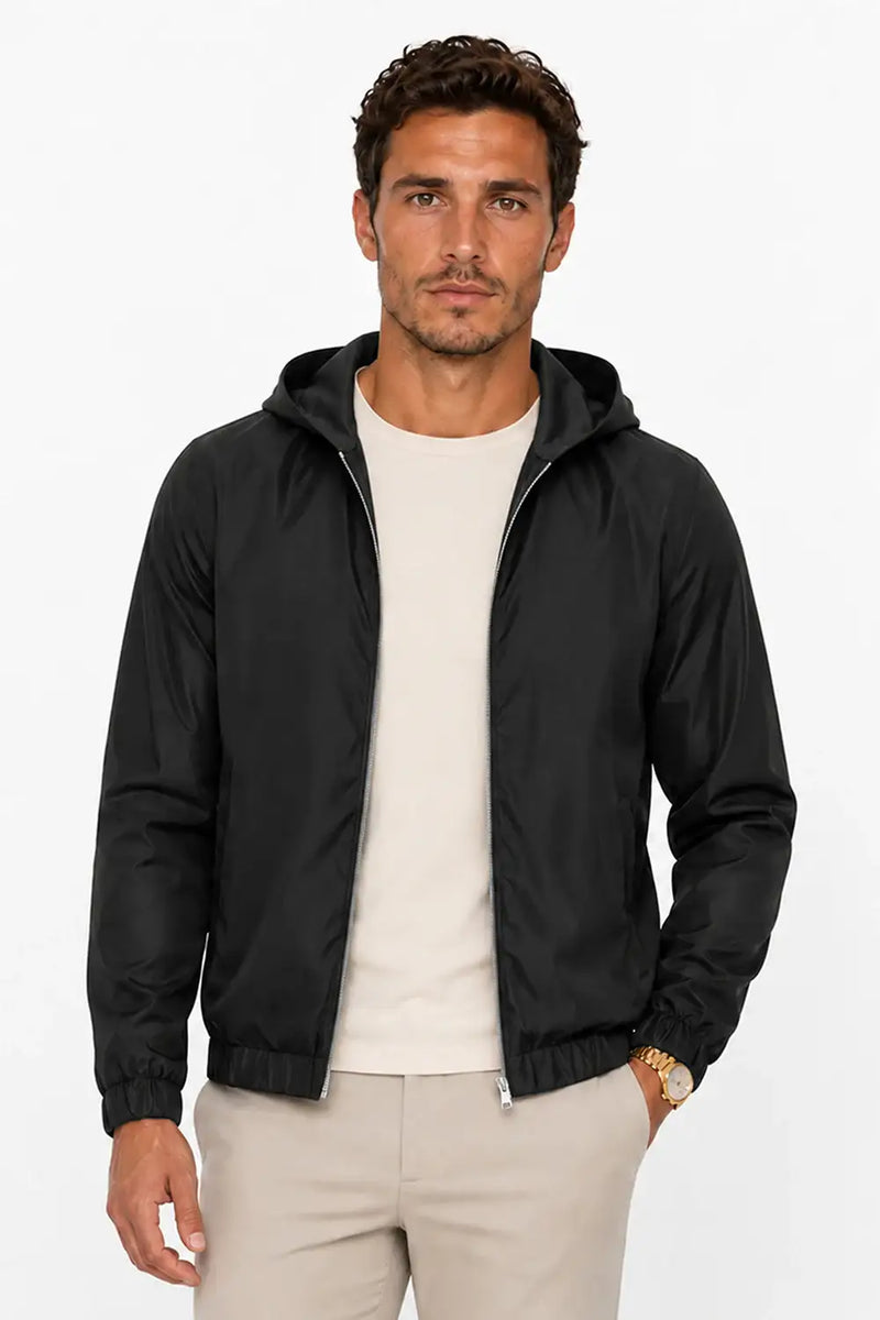 Man wearing black hooded windbreaker jacket with beige chinos, stylish casual outfit